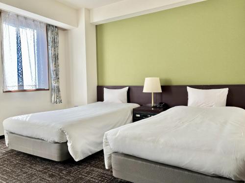 two beds in a room with green walls at Hotel Bougain Villea Sapporo in Sapporo