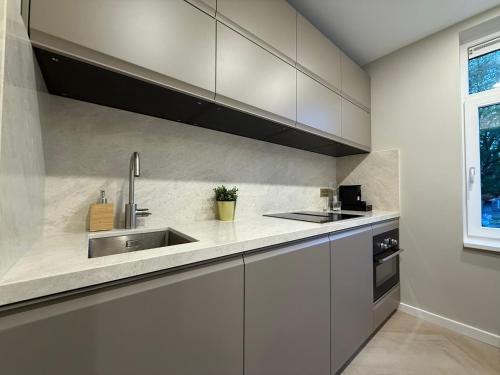a kitchen with white cabinets and a sink at The Stylish Gem of Den Haag Aprt R1 in The Hague