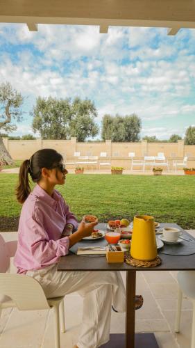 a woman sitting at a table with a plate of food at Casale degli Ulivi by Apulia Hospitality in Fasano