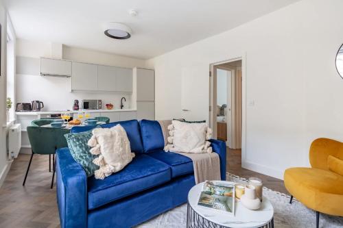a living room with a blue couch and a kitchen at BnBNova - 1BR - St Paul's & Barbican in London