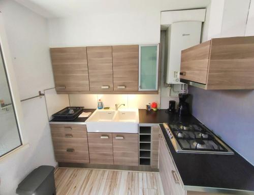 Elle comprend une petite cuisine avec des placards en bois et un évier. dans l'établissement AZEMA : Cocon tranquille avec terrasse proche du centre, à Montpellier