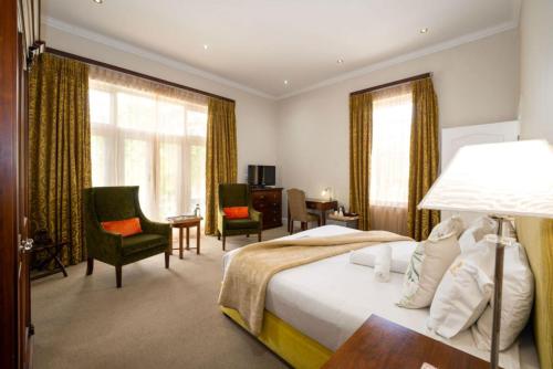 a hotel room with a bed and a desk and chairs at Wild Mushroom Country House in Stellenbosch