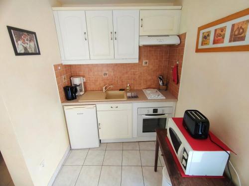 une petite cuisine avec des armoires blanches et un micro-ondes dans l'établissement Havre de paix au cœur du village de Florensac., à Florensac