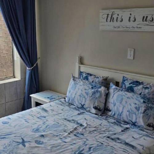 a bedroom with a bed with blue sheets and pillows at Peacehaven's Top Floor Gem 703 in Scottburgh