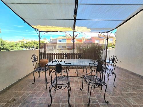 une table et des chaises sur une terrasse avec un auvent dans l'établissement VILLA DES MUSES : Havre de paix avec 3 chambres et jardin arboré à 2 pas du centre, à Marseillan