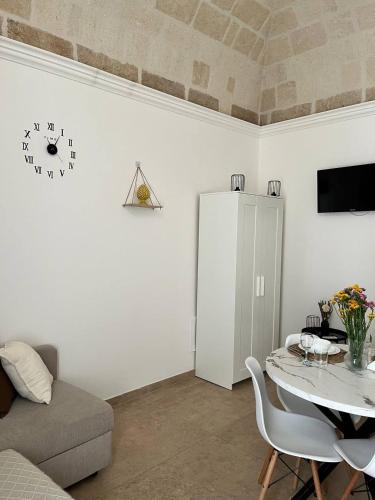 a living room with a table and a clock on the wall at Bien-être Exclusive Apartment in Taranto