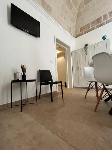 a living room with two chairs and a tv on a wall at Bien-être Exclusive Apartment in Taranto