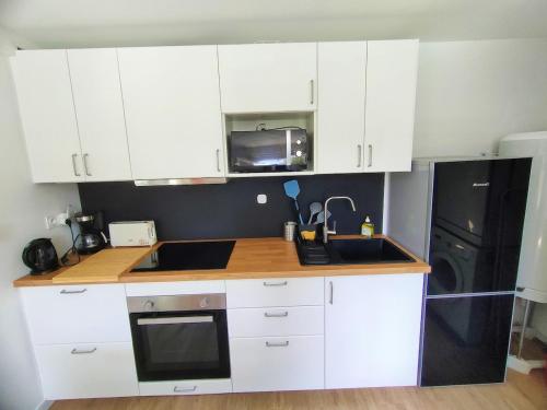 une cuisine avec des armoires blanches et un réfrigérateur noir dans l'établissement Une Oasis de détente, un cocon avec piscine privée., à Marseillan