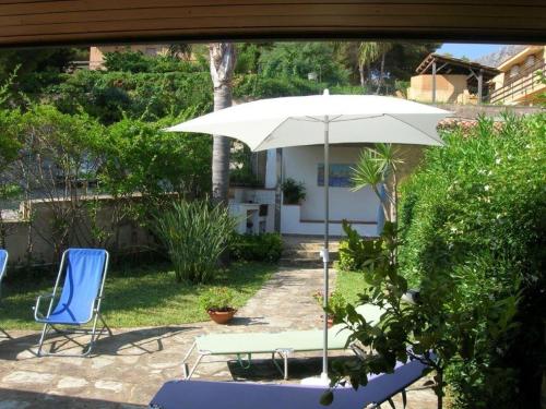 a patio with a table and an umbrella and chairs at Scopello Beach in Scopello