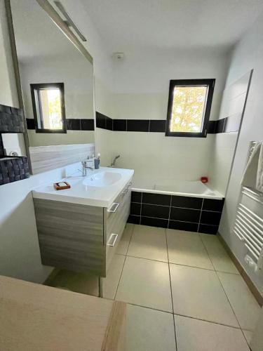 une salle de bain avec un lavabo, une baignoire et un miroir dans l'établissement Peaceful house for 6 people 400 m from the sea, à Bretignolles-sur-Mer