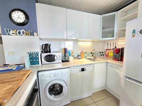 une cuisine avec un lave-linge et un micro-ondes dans l'établissement Rochelongue : Piscine, plage, loisirs, restaurants, au Cap d'Agde