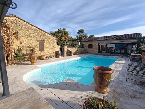 une grande piscine bleue devant un immeuble dans l'établissement Maison près de Sarlat, à Sarlat-la-Canéda