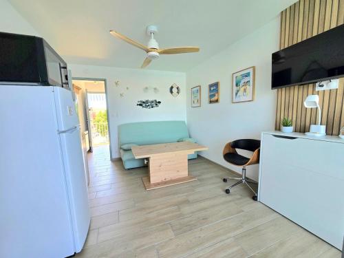 - une cuisine avec un réfrigérateur et une table dans la chambre dans l'établissement LA TORTUE : Terrasse avec vue sur le Port en Studio Cabine, au Cap d'Agde