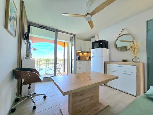 une cuisine avec une table en bois et un réfrigérateur dans l'établissement LA TORTUE : Terrasse avec vue sur le Port en Studio Cabine, au Cap d'Agde