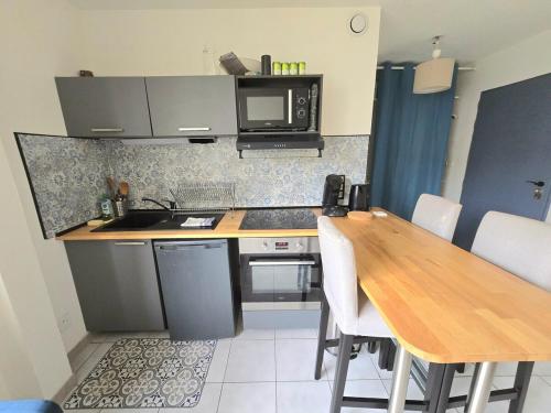 une petite cuisine avec une table et un micro-ondes dans l'établissement ACADIE : Studio quartier Antigone, ascenseur tramway calme, à Montpellier