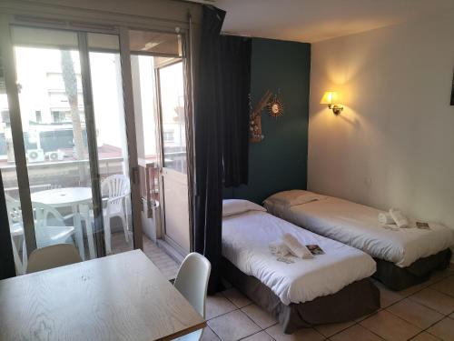 Cette chambre comprend 2 lits, une table et un balcon. dans l'établissement Résidence Graziella studio 208, à Juan-les-Pins
