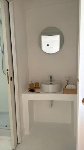 a white bathroom with a sink and a mirror at La Terrazza sul Faro in Porto Empedocle