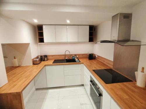 une cuisine avec des armoires blanches et un évier dans l'établissement LA LOGE : Un écrin de modernité spacieux avec 4 chambres au Cœur de Ville, à Montpellier
