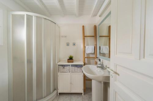 Un baño blanco con lavabo y espejo. en Villa Orea Beachfront by Mykonos Mood, en Kalafatis