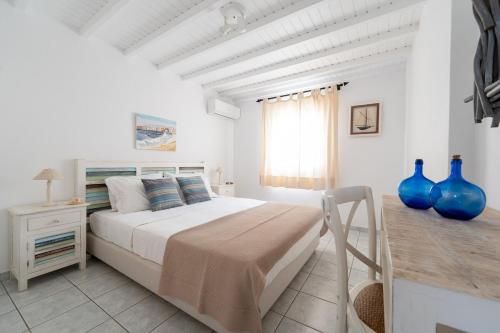 Una habitación blanca con una cama y una ventana en Villa Orea Beachfront by Mykonos Mood, en Kalafatis