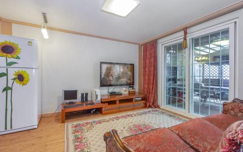 a living room with a couch and a refrigerator at Spa Pension Basso in Sokcho