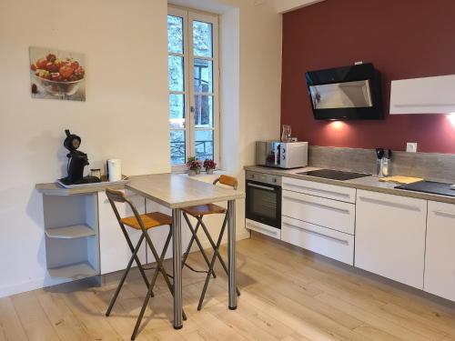 une cuisine avec des armoires blanches et une table avec des chaises dans l'établissement Le SAINT LEGER - Chambery centre, à Chambéry