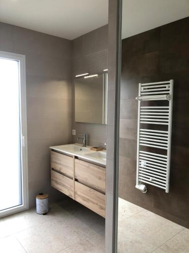 une salle de bain avec un lavabo et un miroir dans l'établissement Maison neuve spacieuse - 6 pers - proche St Gilles, à Givrand