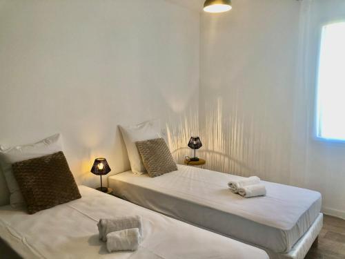 - 2 lits dans une chambre blanche avec 2 lampes dans l'établissement Maison neuve spacieuse - 6 pers - proche St Gilles, à Givrand