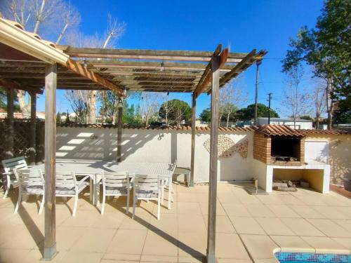 une terrasse avec des chaises blanches et une pergola en bois. dans l'établissement LA VILLA du GRAU D'AGDE : Le rêve : Détente, plage et gastronomie, au Grau-dʼAgde