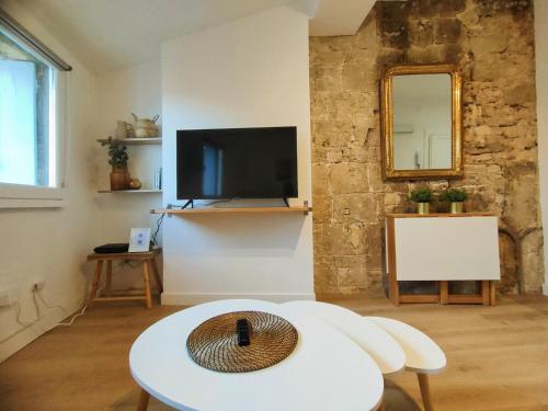 un salon avec une table et une télévision dans l'établissement BARNABE : Nid douillet perché en plein centre historique., à Montpellier