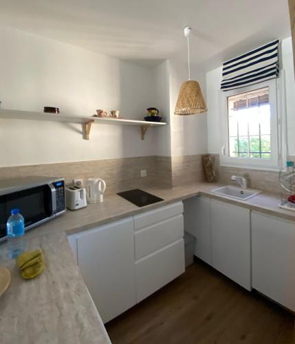 une cuisine avec des armoires blanches, un évier et un micro-ondes dans l'établissement Emeraude, à Saint-Raphaël