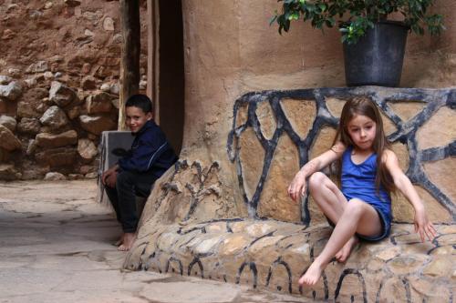 a young girl sitting on a rock bench with a man sitting on a laptop at Kasbah Maison D’hôte Lalla Zahra in Aït Baha