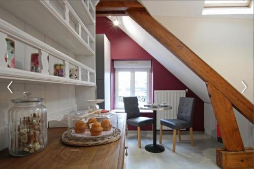 une pièce avec une table, des chaises et un escalier dans l'établissement Cour historique La cour des trois rois 1, à Villedieu-les-Poêles