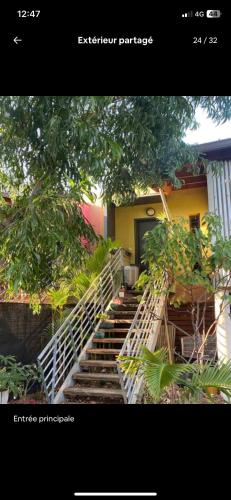 a staircase leading up to a yellow building with trees at Chambre De L étang in Saint-Paul