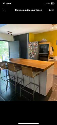 a kitchen with a counter with chairs around it at Chambre De L étang in Saint-Paul