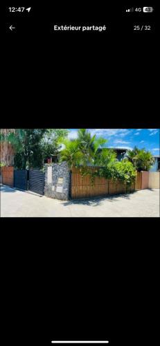 a picture of a fence with palm trees behind it at Chambre De L étang in Saint-Paul