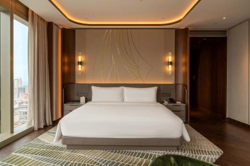 a bedroom with a white bed and a large window at MGM Qingdao in Qingdao