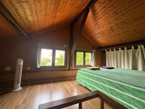- une chambre en bois avec un lit vert dans l'établissement Caprice, à Lacanau-Océan