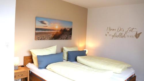 a bedroom with a bed with blue and white pillows at Ferienwohnung Seewiefke in Holtgast