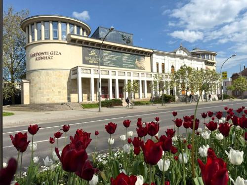 un edificio con flores rojas y blancas delante de él en HelloWine Apartman III, en Eger