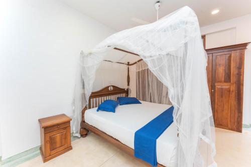 a bedroom with a bed with a mosquito net at Hotel Coconut Bar Sea Lodge in Beruwala