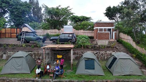 a group of people standing in a yard with tents at Twin Lakes Eco Lodge Campsite in Rubirizi