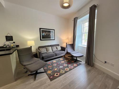 a living room with a couch and chairs and a window at King’s stable 2 rooms in Edinburgh