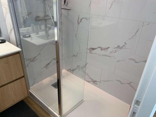 une douche avec une porte vitrée dans une salle de bain dans l'établissement Le Rocher de la Corniche Saint Hilaire de Riez, à Saint-Hilaire-de-Riez