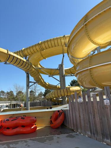 un toboggan aquatique dans une aire de jeux avec des gilets de sauvetage orange dans l'établissement Rêves de pins, à Lit-et-Mixe