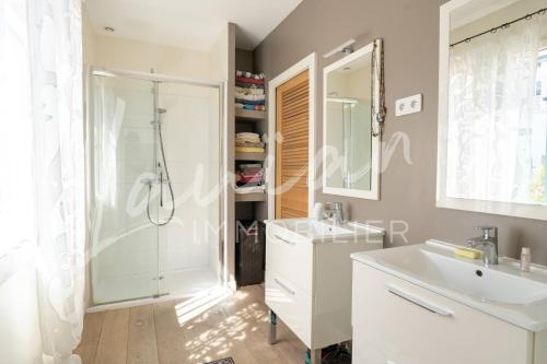 La salle de bains est pourvue d'une douche et d'un lavabo blanc. dans l'établissement Villa Silvana, à Anglet