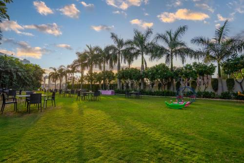 a park with a playground and tables and palm trees at Hotel Chandrawati Palace in Ābu Road