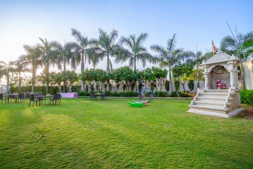 a garden with a gazebo and tables and palm trees at Hotel Chandrawati Palace in Ābu Road