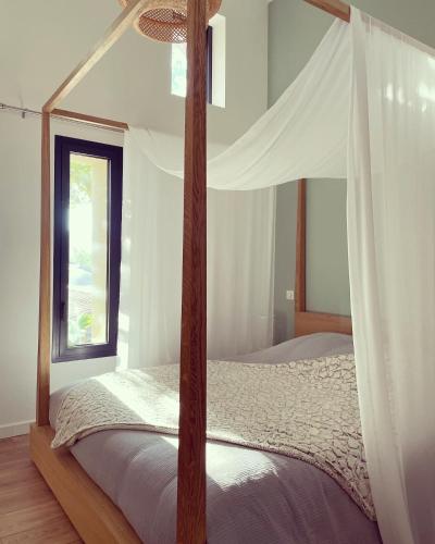 - une chambre avec un lit à baldaquin et une fenêtre dans l'établissement Nuit romantique avec jacuzzi privé !, à Noé