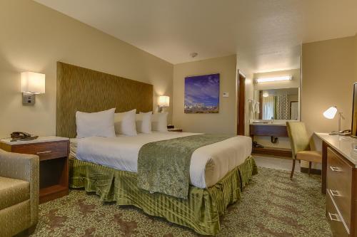 a hotel room with a large bed and a chair at Vagabond Inn Bishop in Bishop